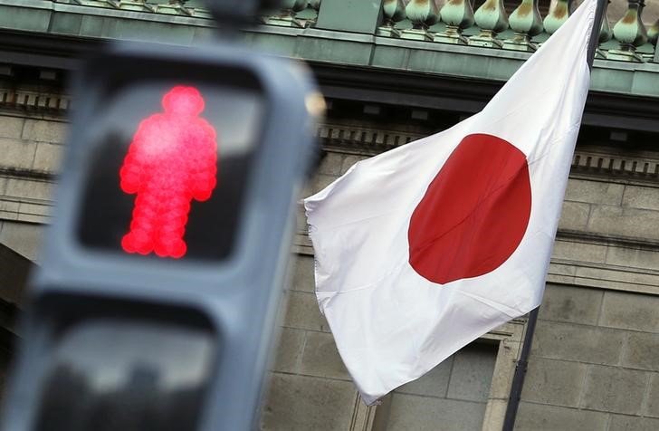 © Reuters. Japan's national flag is seen behind a traffic signal of a red man at the Bank of Japan headquarters in Tokyo