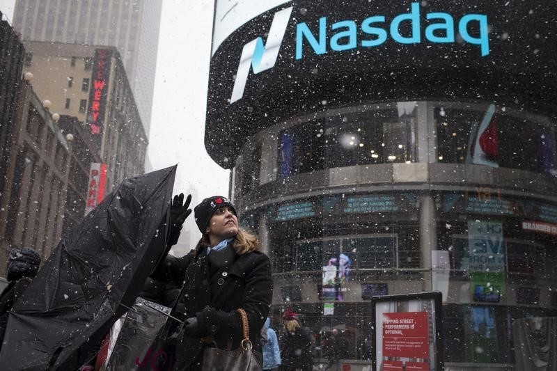 © Reuters. A woman's umbrella turns inside out as she walks past the Nasdaq MarketSite during a snow storm in Times Square, Midtown New York 