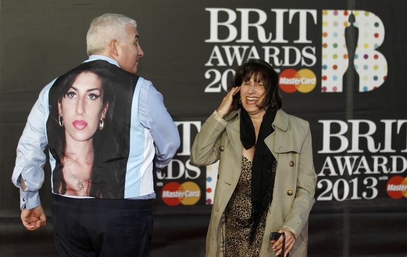 © Reuters. Mitch and Janis Winehouse, the father and mother of the late singer Amy Winehouse, laugh as they arrive for the BRIT Awards at the O2 Arena in London