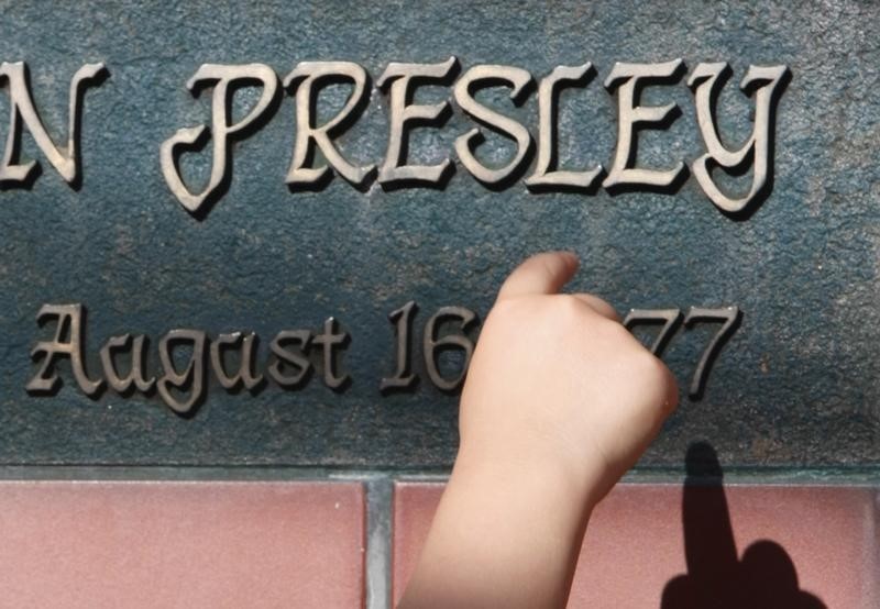 © Reuters. A child points at a plate with Elvis Presley's name during a Presley memorial event in Tokyo