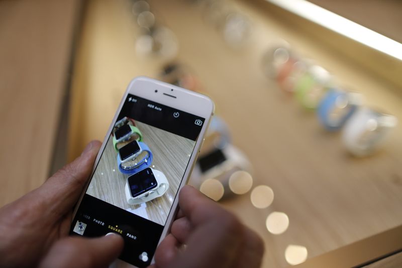 © Reuters. File photo of a customer using his iPhone to take pictures of the new Apple Watch displayed at an Apple Store in Paris