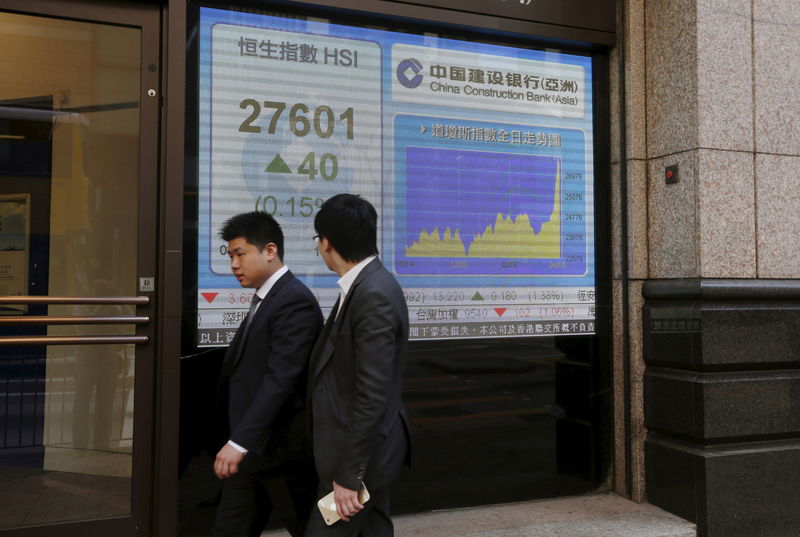 © Reuters. People walk past a panel displaying the benchmark Hang Seng Index during afternoon trading outside a bank in Hong Kong