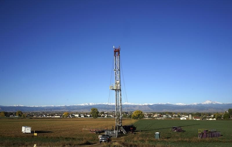 © Reuters. Workers drill a new oil well in a farm field within sight of houses near the town of Longmont