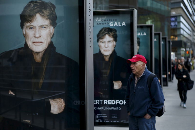 © Reuters. A man looks at posters of actor Robert Redford during the Chaplin award at Alice Tully Hall in New York