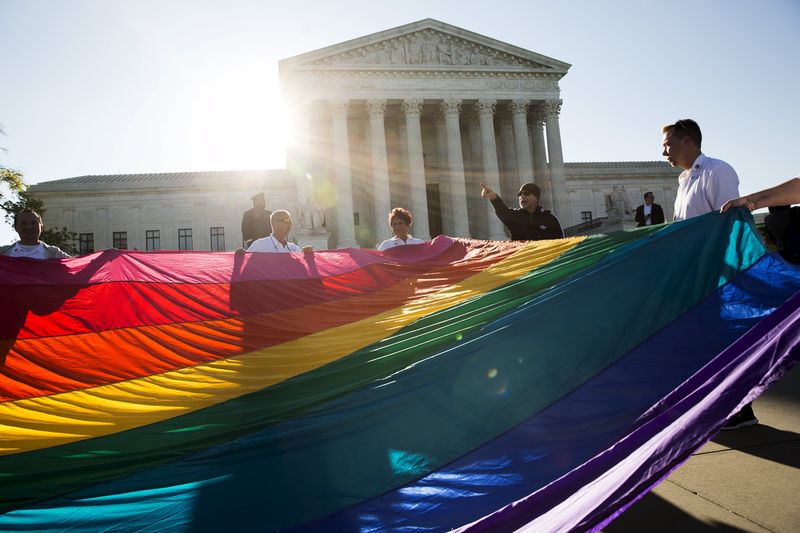 © Reuters. Gay marriage supporters hold a gay rights flag in front of the U.S. Supreme Court before a hearing about gay marriage