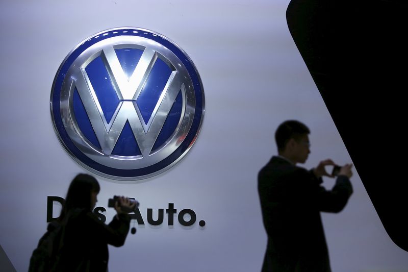 © Reuters. Guests stand next to a Volkswagen logo at the stage of the company at the 16th Shanghai International Automobile Industry Exhibition in Shanghai