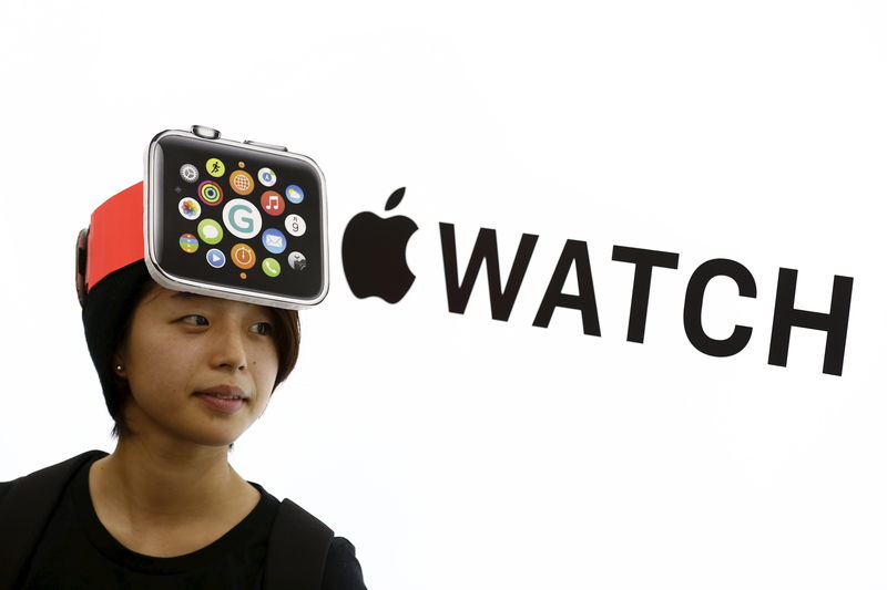 © Reuters. Woman wearing a mock-up Apple Watch stands in front of Apple sign at electronics store in Tokyo