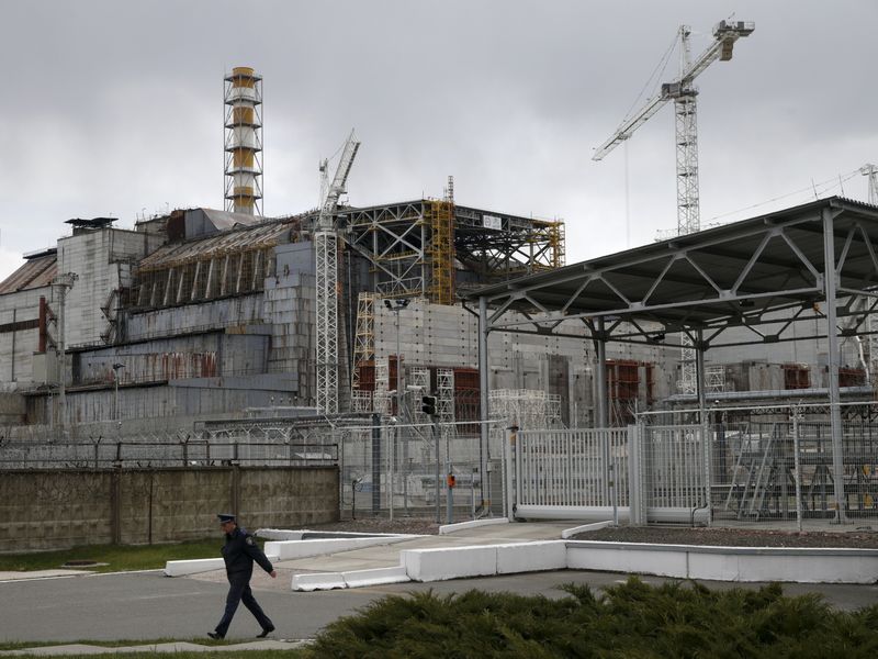 © Reuters. A man walks in front of the sarcophagus covering the damaged fourth reactor at the Chernobyl nuclear power plant