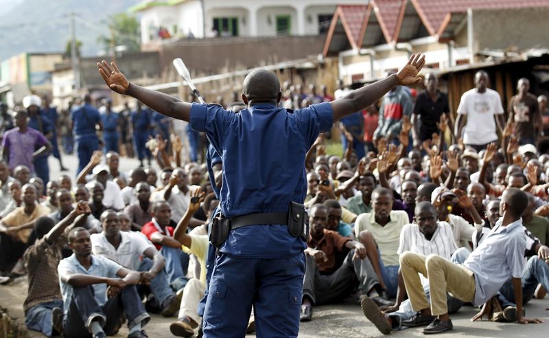 © Reuters. Riot police officer speaks to residents participating in street protests in Burundi's capital Bujumbura