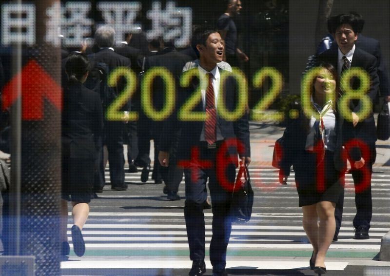 © Reuters. People are reflected in an electronic board displaying Japan's Nikkei share average outside a brokerage in Tokyo 