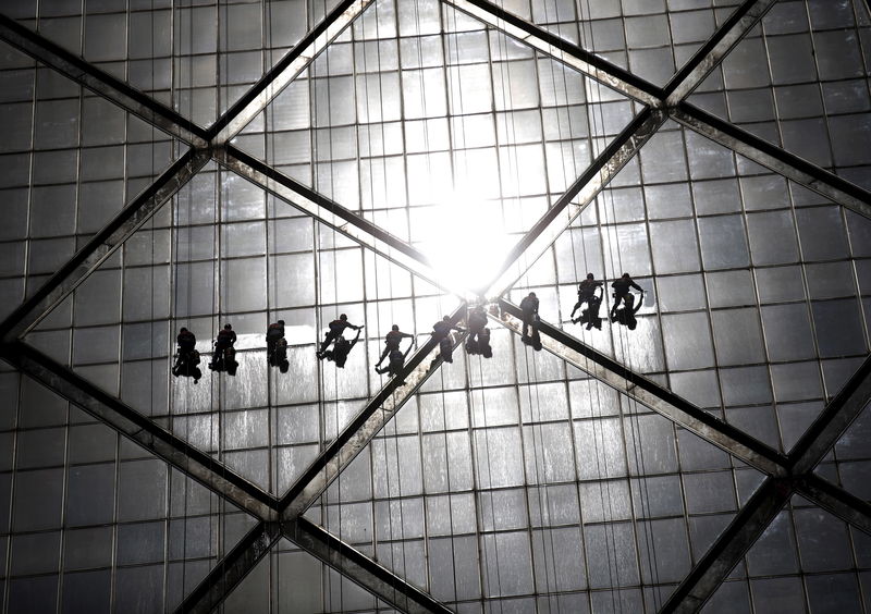 © Reuters. Workers clean windows of a building at a commercial district in Beijing