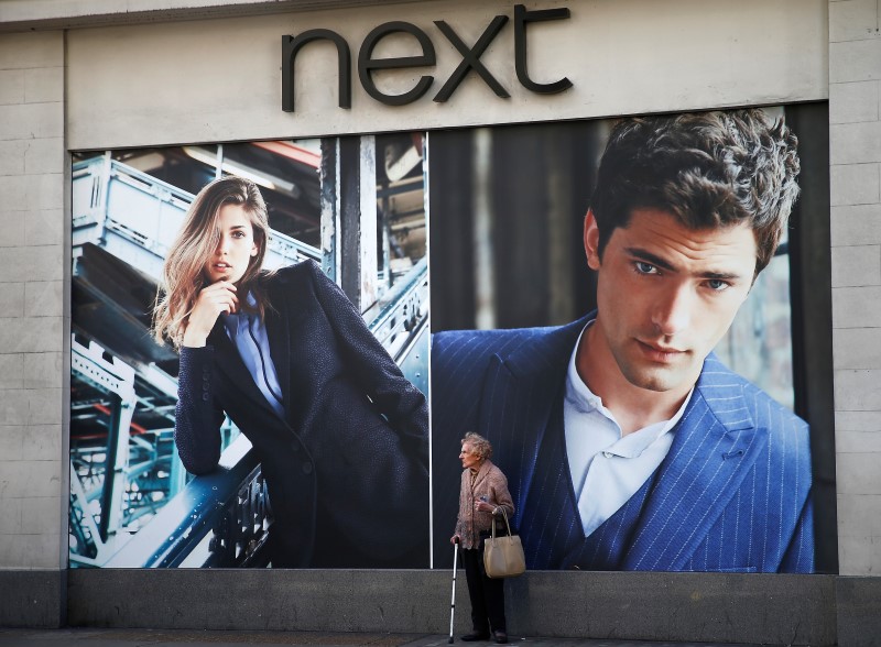 © Reuters. A woman pauses under advertising display outside a branch of clothing retailer Next in London's West End