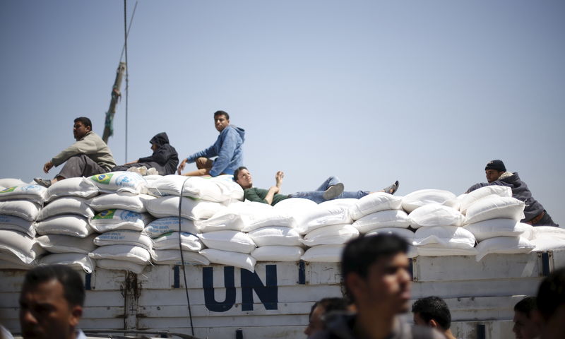 © Reuters. Palestinians, sitting atop a truck loaded with sacks of flour, watch a demonstration calling on rival Palestinian leaders to end their political division, in Gaza City 