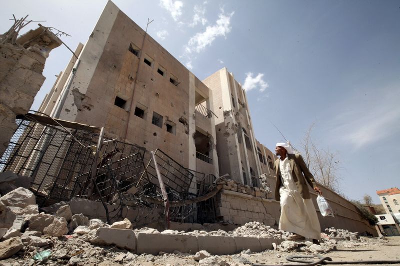 © Reuters. A man looks at a school destroyed by an air strike as he flees his home in Sanaa 