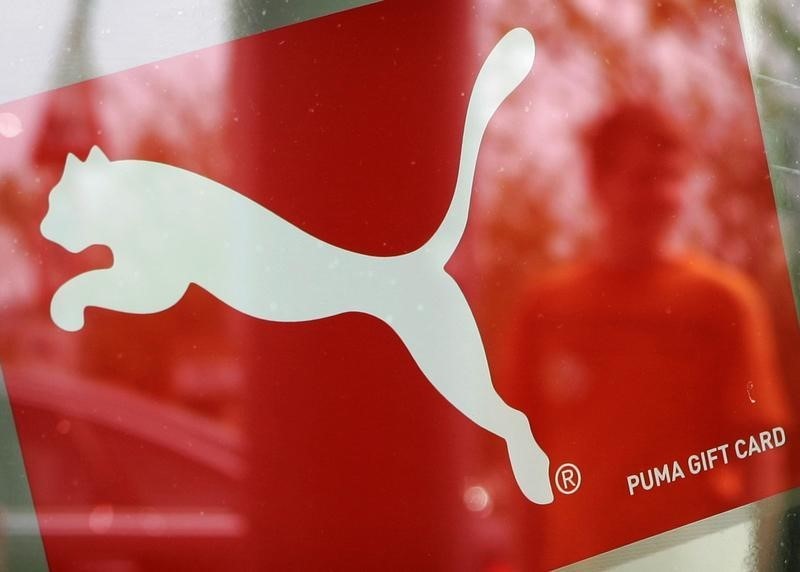 © Reuters. A man is reflected in a window with a Puma sign, at the factory outlet store in Herzogenaurach