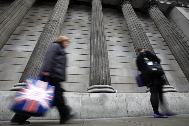 © Reuters. A woman carries a shopping bag decorated with a Union flag past the columns of the Bank of England in the City of London