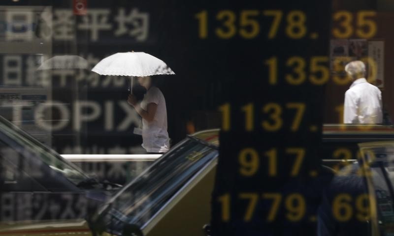 © Reuters. People are reflected on a stock quotation board displaying Japan's Nikkei average and other markets' indices outside a brokerage in Tokyo