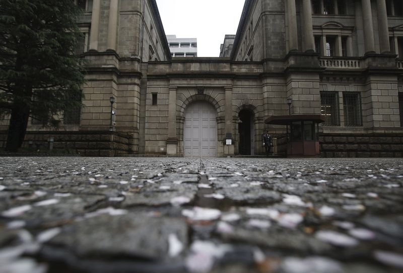 © Reuters. A security guard walks out from the Bank of Japan headquarters building as petals of cherry blossoms are seen on the ground in Tokyo