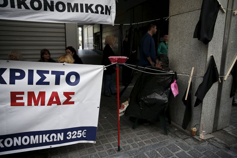 © Reuters. Broom is seen supporting a banner during a protest by cleaning workers working in the finance ministry over pay issues in their sector, outside the ministry building in Athens 