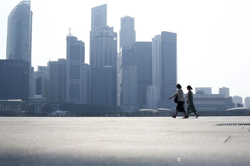 © Reuters. People walk past the skyline of the financial district on a hazy day in Singapore