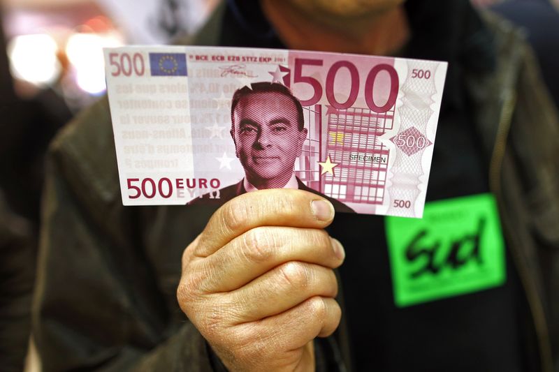 © Reuters. A labour council representative holds a facsimile 500 euros note with the portrait of Carlos Ghosn, Chairman and CEO of the Renault-Nissan Alliance, before the French carmaker Renault's shareholders general meeting in Paris