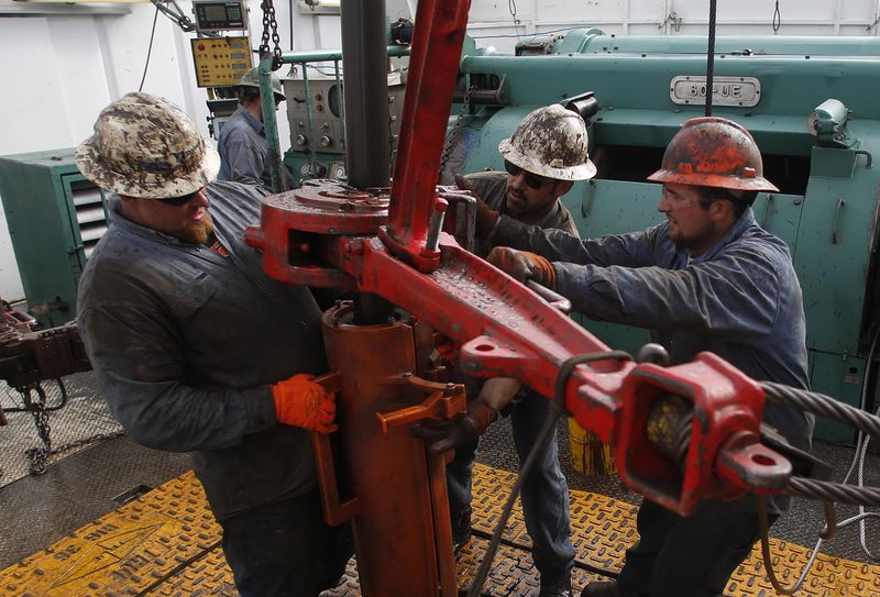 © Reuters. Roughnecks wrestle pipe on a True Company oil drilling rig outside Watford