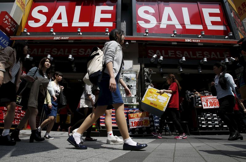 © Reuters. A shop clerk carries a box under sale signboards at a shoes store in Tokyo