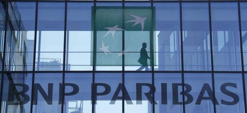 © Reuters. A man walks behind the logo of BNP Paribas in a building in Issy-les-Moulineaux, near Paris