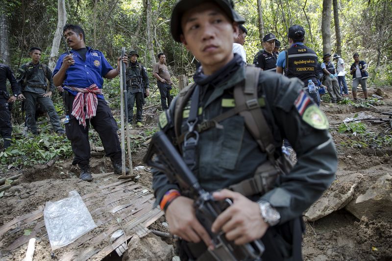 © Reuters. Security forces and rescue workers watch as human remains are retrieved from a mass grave at an abandoned camp in Thailand's southern Songkhla province