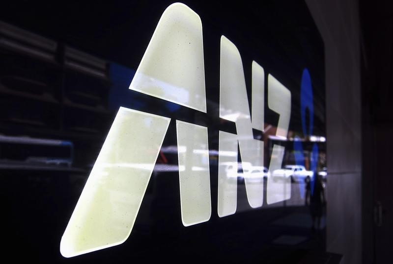 © Reuters. A man is reflected in an ANZ logo as he walks past a branch located in a Sydney suburb