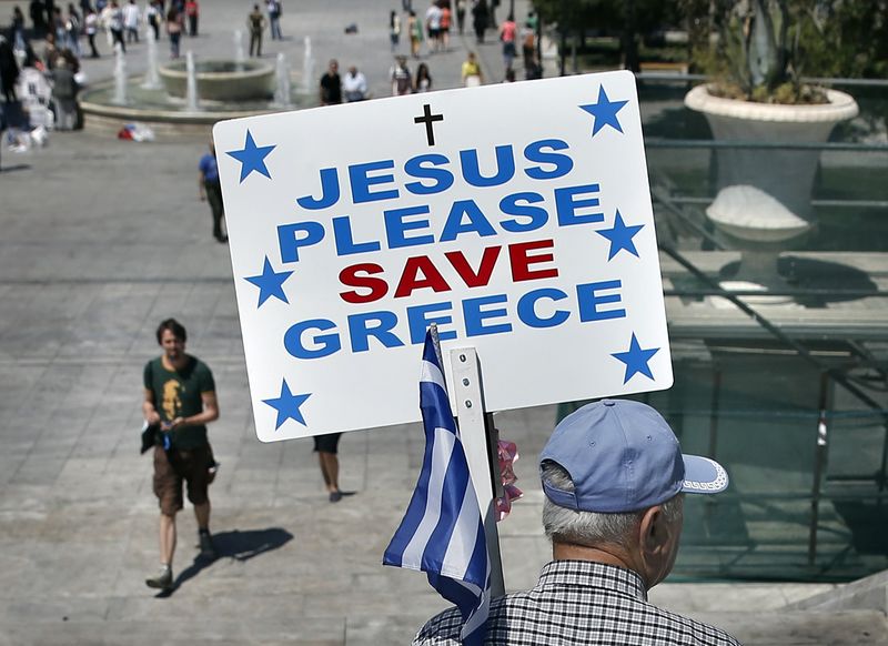 © Reuters. A man holding a Greek national flag and a placard walks in Constitution Square in Athens