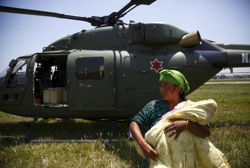 © Reuters. Mulher carregando seu filho após ser resgatada por helicóptero no distrito de Sindhupalchok