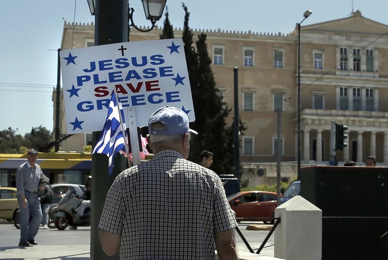 © Reuters. Homem com bandeira grega e cartaz na praça da Constituição, com o Parlamento de fundo, em Atenas