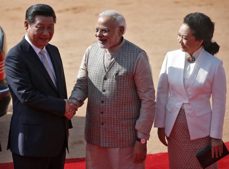 © Reuters. India's PM Modi and China's President Xi shake hands as Xi's wife Peng looks on during Xi?s ceremonial reception in New Delhi