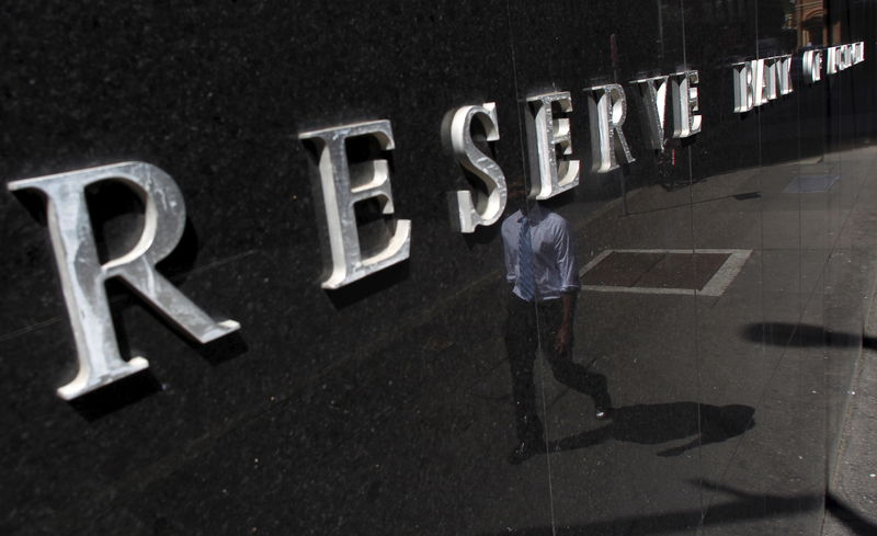 © Reuters. File photo of an office worker reflected on the building of the Reserve Bank of Australia in central Sydney