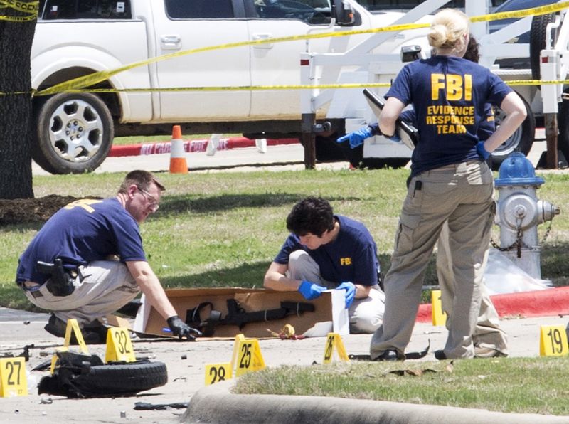 © Reuters. FBI investigators collect evidence, including a rifle, where two gunmen were shot dead after their bodies were removed in Garland