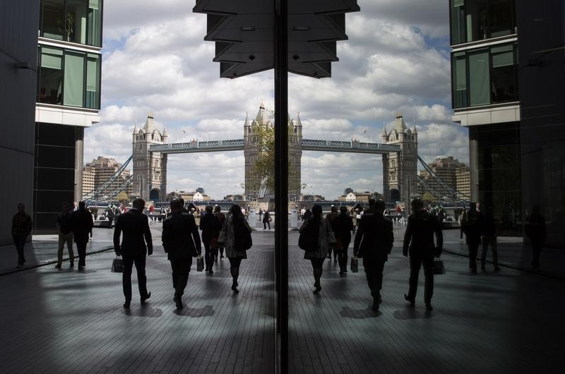 © Reuters. City workers are reflected in a window as they pass near the Tower of London