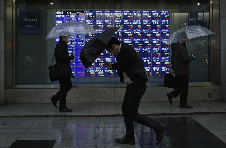 © Reuters. Pedestrians walk past an electronic board outside a brokerage in Tokyo
