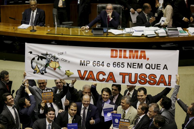© Reuters. Deputados seguram cartaz contra votação a MP 664 e 665 na Câmara dos Deputados, em Brasília