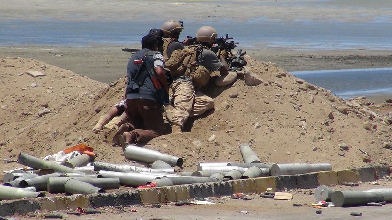 © Reuters. Combatente se posiciona atrás de soldados em Áden