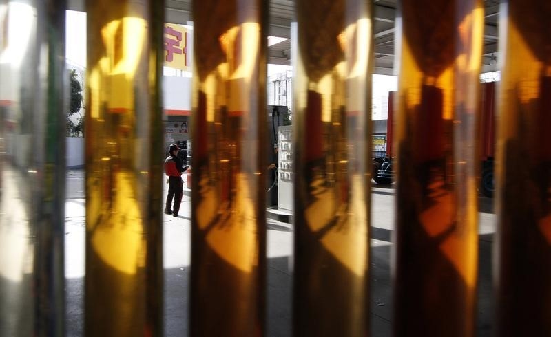 © Reuters. An employee of a petrol station is seen between samples of engine oil at a gas station in Tokyo