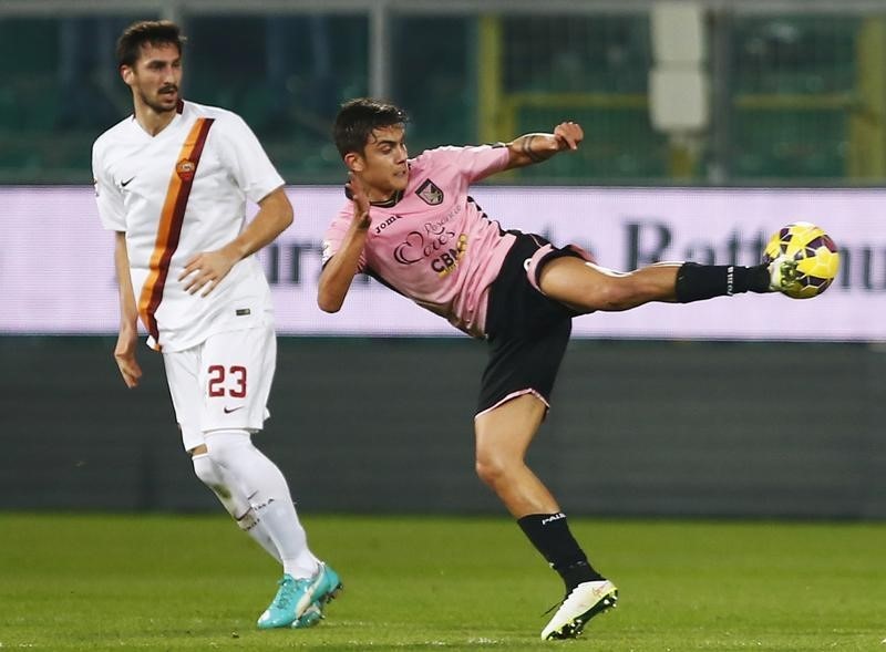 © Reuters. Palermo's Dybala shoots a ball as AS Roma's Astori looks during their Italian Serie A soccer match in Palermo