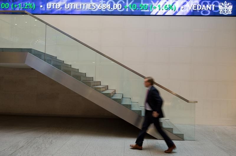 © Reuters. A man walks under an electronic information board at the London Stock Exchange in the City of London