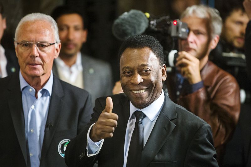 © Reuters. Pele and Franz Beckenbauer pose for photos after they ceremonially turned on lights of Empire State Building during event to celebrate start of New York Cosmos 2015 season, in New York