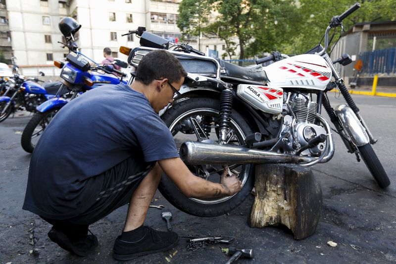 © Reuters. Mecânico conserta moto em rua de Caracas 