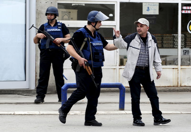 © Reuters. Macedonian policeman speaks to a man near a police checkpoint in Kumanovo