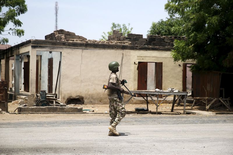 © Reuters. A soldier walks past a burnt building in Michika town