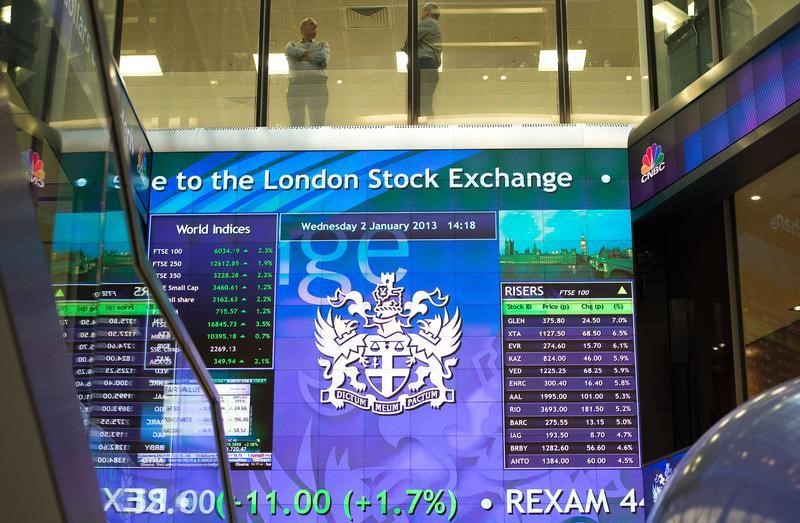 © Reuters. Workers speak above an electronic information board at the London Stock Exchange in the City of London