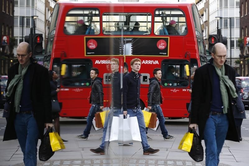 © Reuters. Shoppers are reflected in a window as they carry bags along Oxford street during the final weekend of shopping before Christmas in London