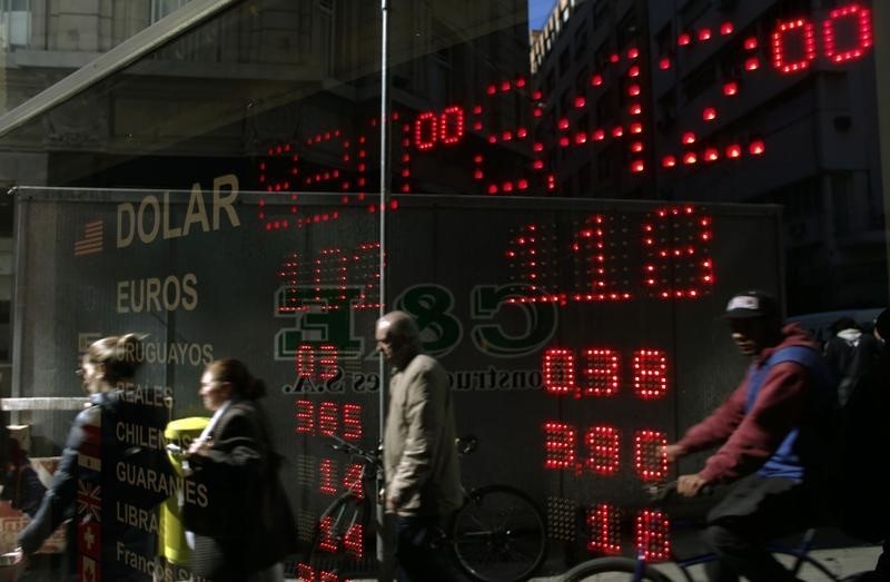 © Reuters. People are reflected in the glass window of a currency exchange store in Buenos Aires' financial district